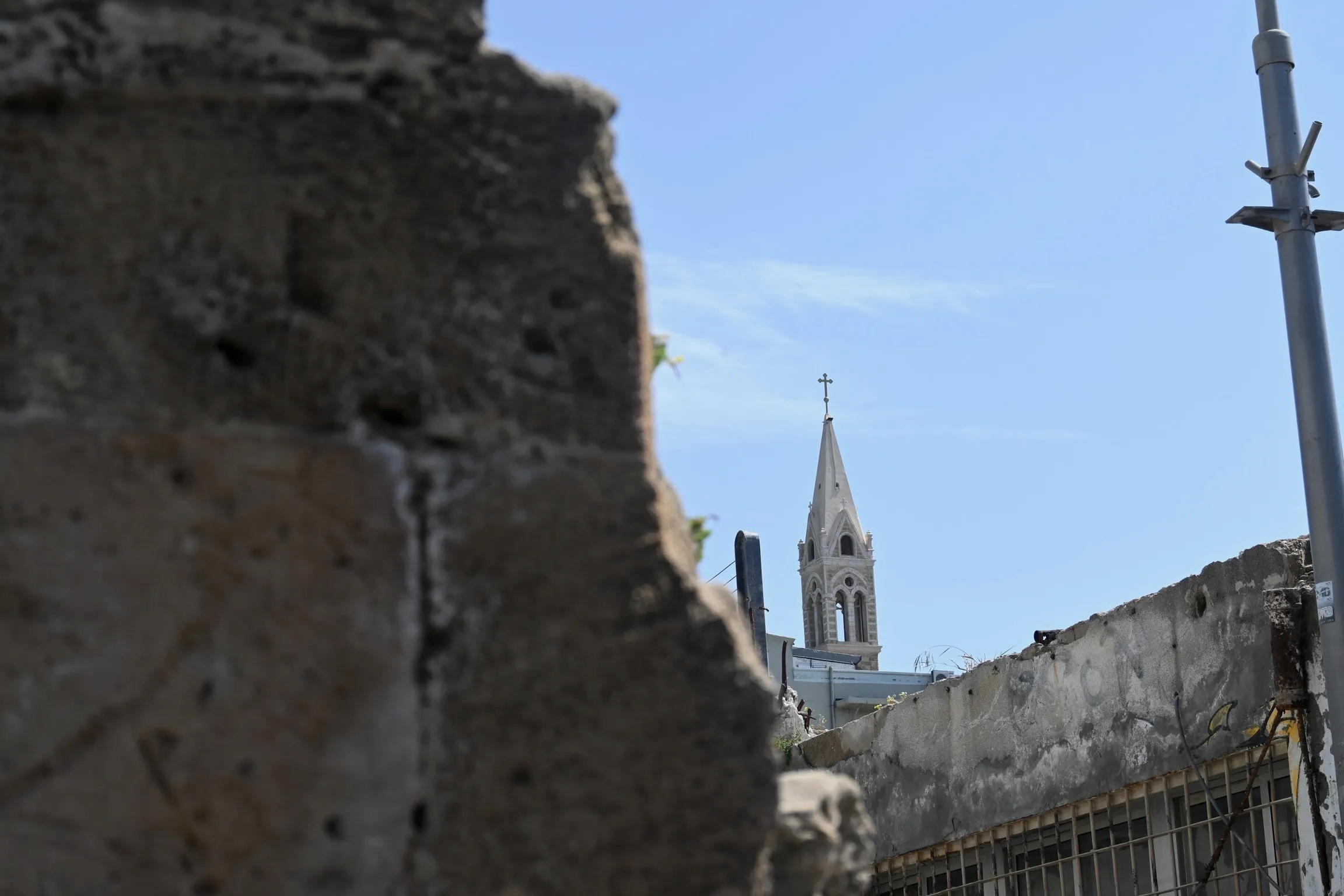A church spire framed by the broken edge of an old stone wall