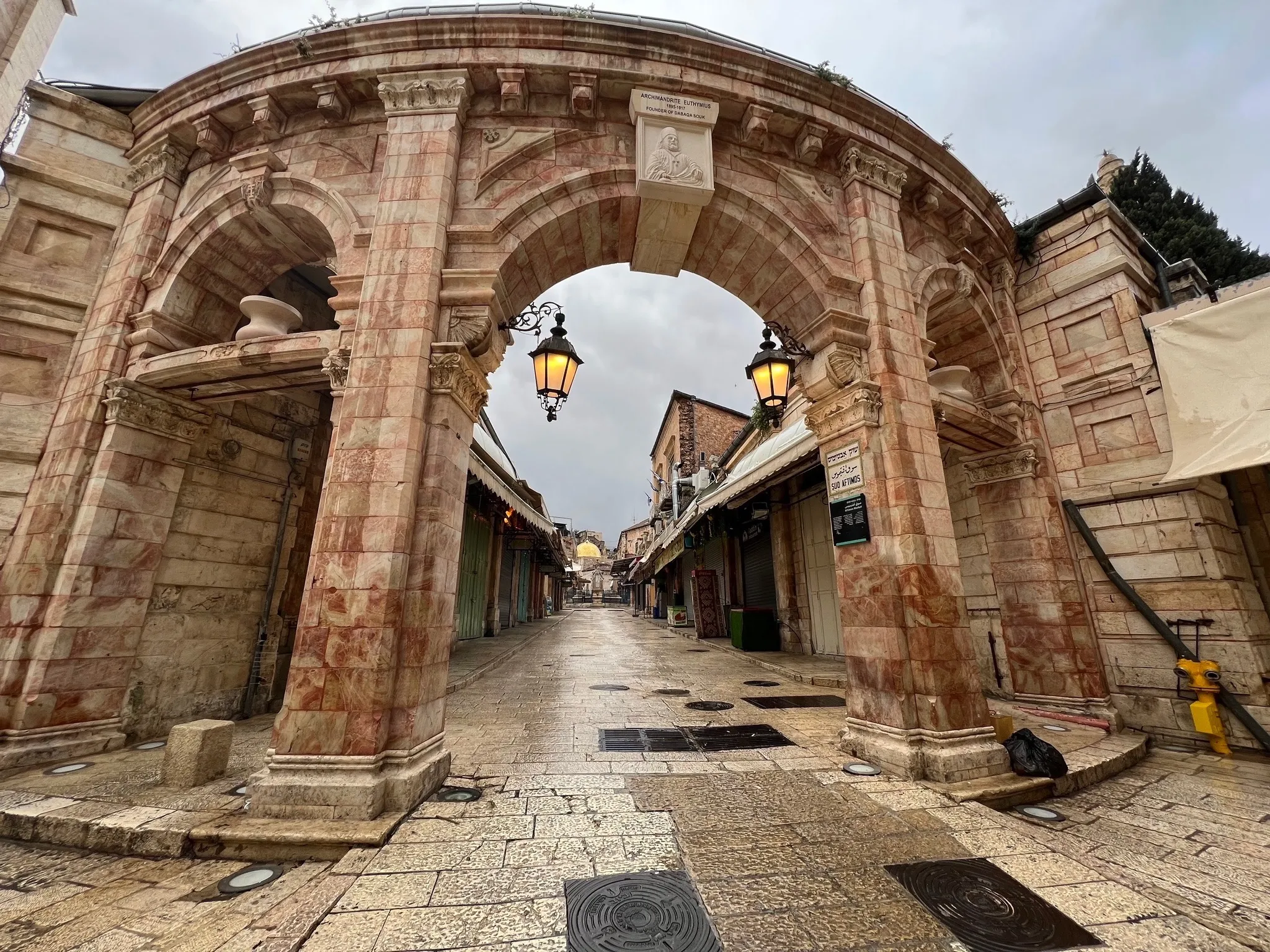 A monumental stone arch over an empty Old City arcade