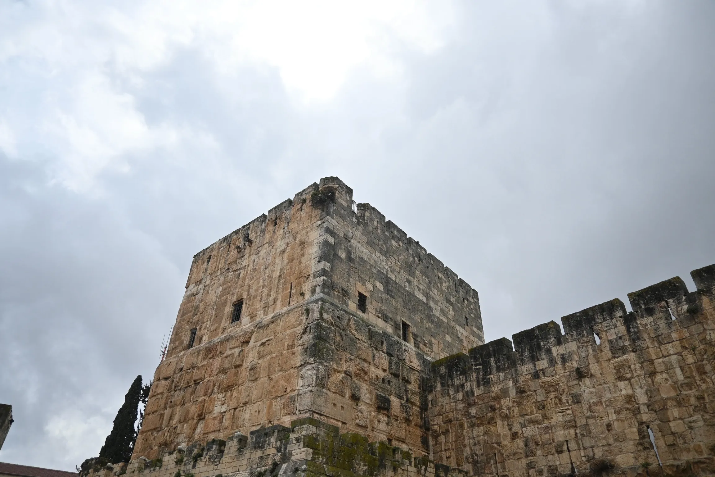 A Jerusalem Old City tower and rampart wall under a storm sky